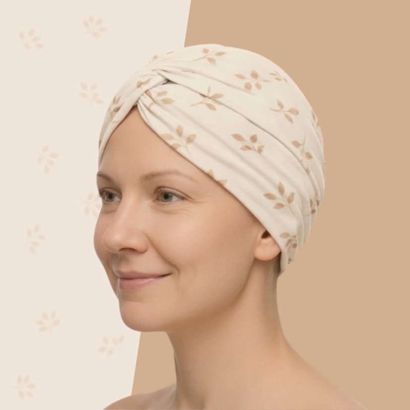 Dizajnový turban po chemoterapii Canaver Belora so vzorom lístkov na krémovom podklade. Unikátny strih zaručí, že ti dokonale sadne a nikde nebude tlačiť.